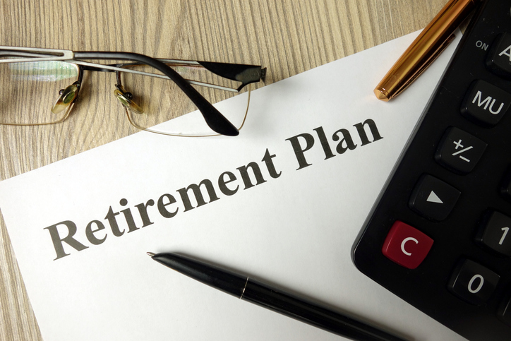 Closeup of a retirement plan with a calculator, pen and glasses.